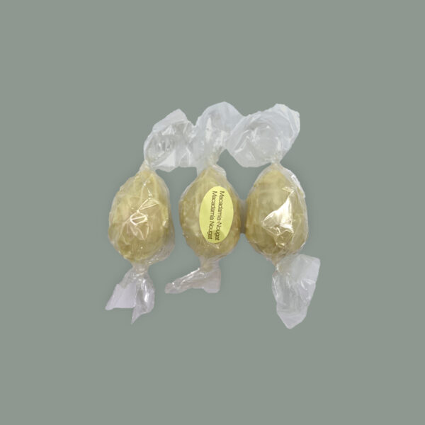 Drei Pralinen aus Weißer Schokolade gefüllt mit Macadamianougat. Gewickelt in Folie