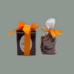 Bitter & Zart Blechdose, verziert mit Logo und Kakafrüchten mit Schleife in Orange, dazu eine Tüte 100% Kakao