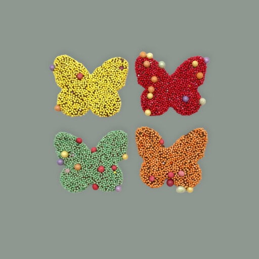 4 Schmetterlinge auf Vollmilchschokolade verziert mit Non Pareilles, farblich je einmal Gelb, Grün, Rot und Orange
