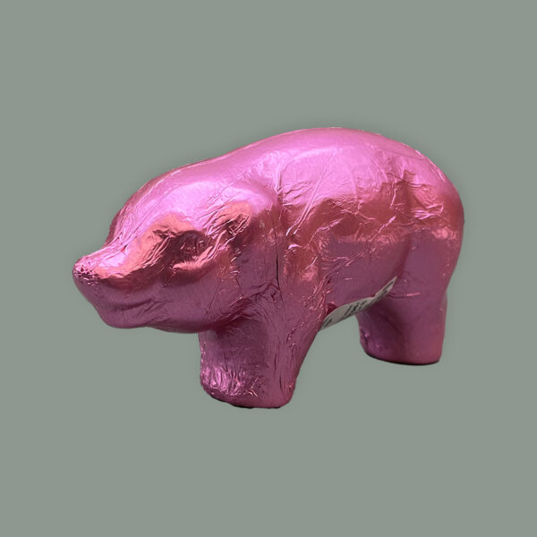 Schokoladen Hohlfigur als Schwein gegossen. Verpackt in rosa glänzendem Stanniol.